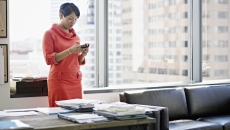 A woman standing at her desk using a smartphone. A woman standing at her desk using a smartphone.