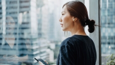 Young urban businesswoman using smartphone in the office in front of windows overlooking the city Young urban businesswoman using smartphone in the office in front of windows overlooking the city