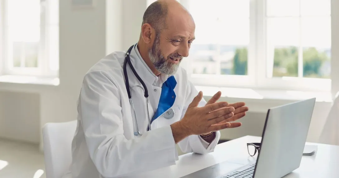 Doctor sitting at a desk looking at a computer Doctor sitting at a desk looking at a computer
