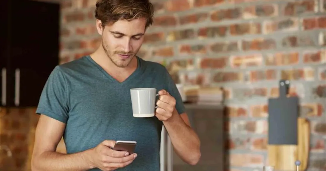 Person holding a cellphone and a cup of coffee Person holding a cellphone and a cup of coffee