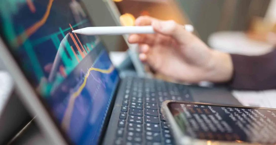 Pen touching a computer screen with financial data Pen touching a computer screen with financial data