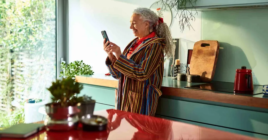 Person standing in their kitchen looking at the phone Person standing in their kitchen looking at the phone