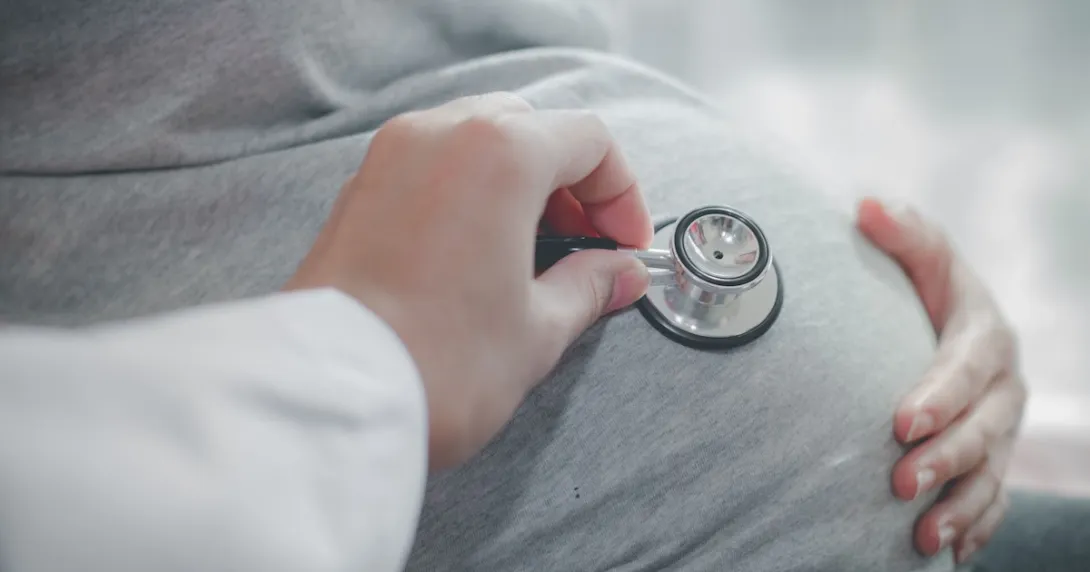A doctor using a stethoscope to assess a pregnant person