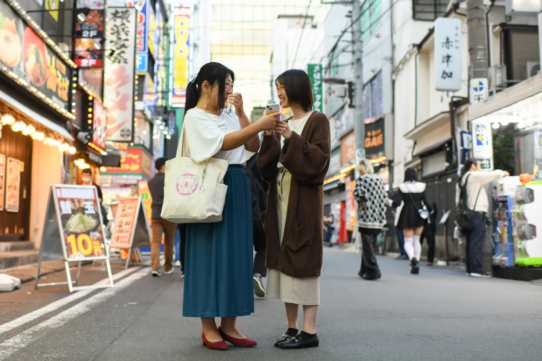 Two persons in the middle of the street talking to each other using a mobile translator app Two persons in the middle of the street talking to each other using a mobile translator app