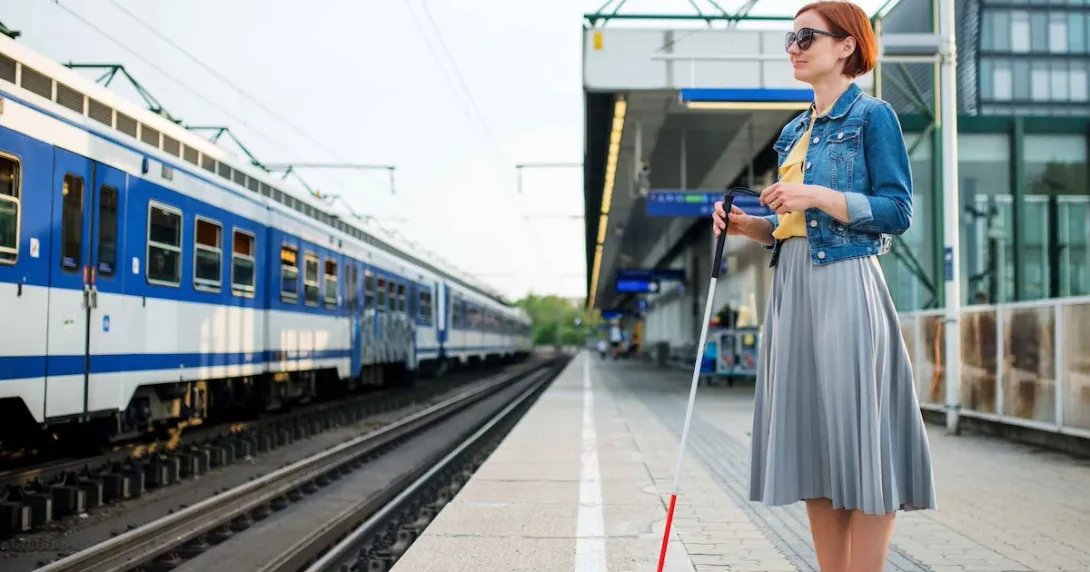 Blind person standing at a train station Blind person standing at a train station