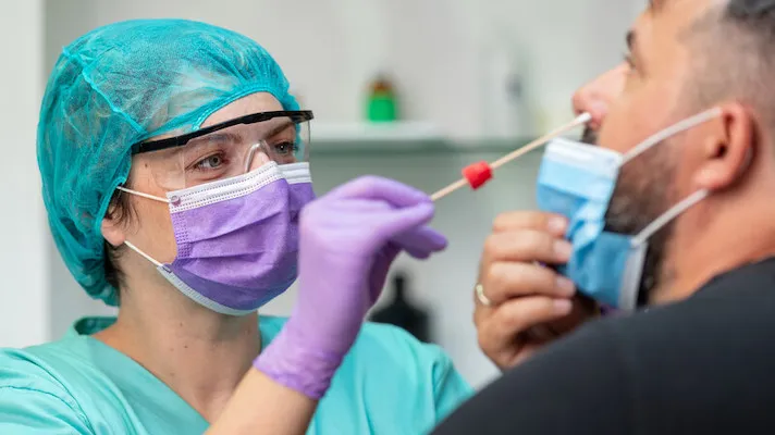 Healthcare worker testing a patient for COVID