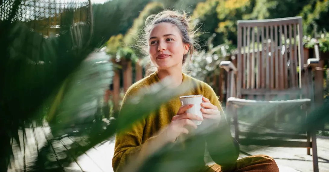 Person sitting outside while drinking a cup of coffee Person sitting outside while drinking a cup of coffee