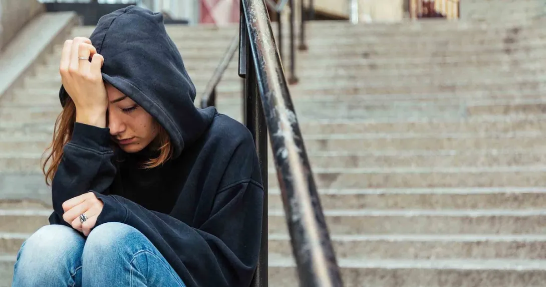 Person sitting on steps with their head in their hand Person sitting on steps with their head in their hand