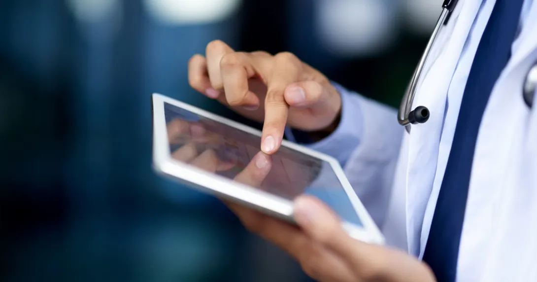 Healthcare provider holding a tablet while wearing a lab coat and stethoscope Healthcare provider holding a tablet while wearing a lab coat and stethoscope