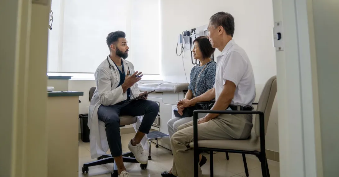 Doctor sitting in an exam room with two patients Doctor sitting in an exam room with two patients