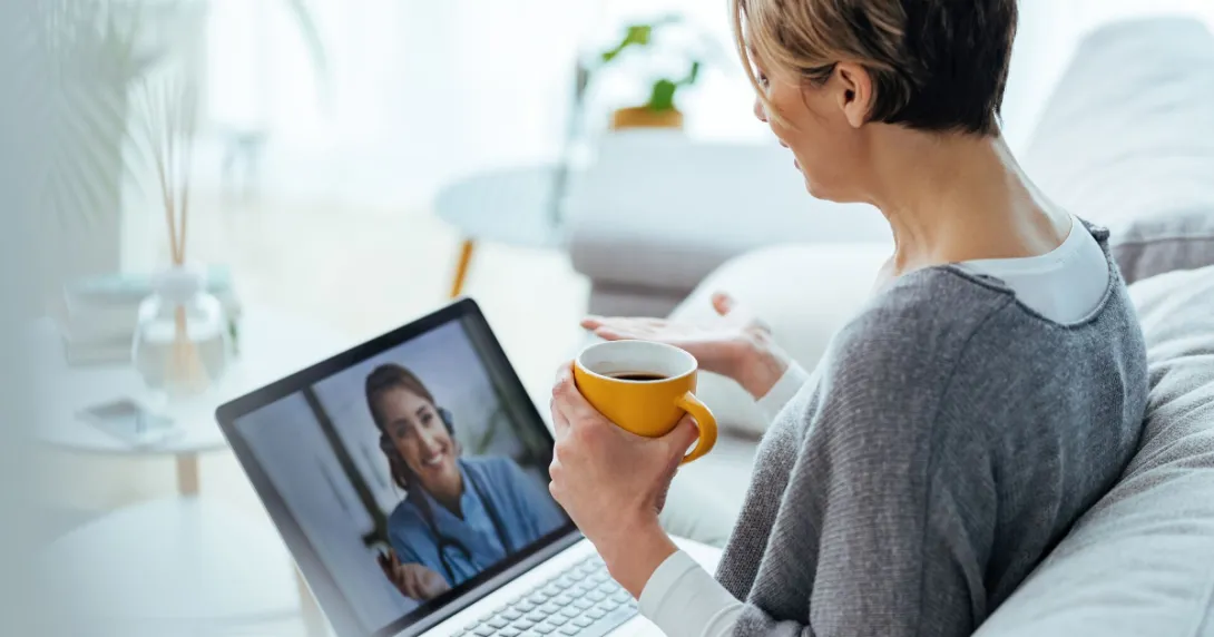 Person sitting on a couch with a laptop on a telehealth video call Person sitting on a couch with a laptop on a telehealth video call