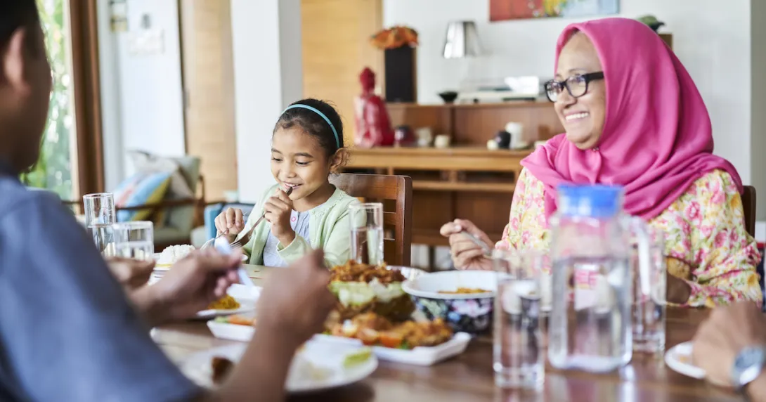 People sitting around a dinner table with food on it People sitting around a dinner table with food on it