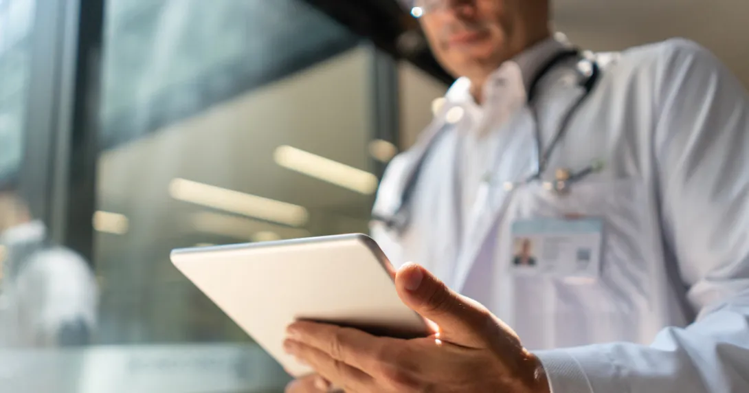 Doctor holding a tablet while in a lab coat with a stethoscope around their neck Doctor holding a tablet while in a lab coat with a stethoscope around their neck