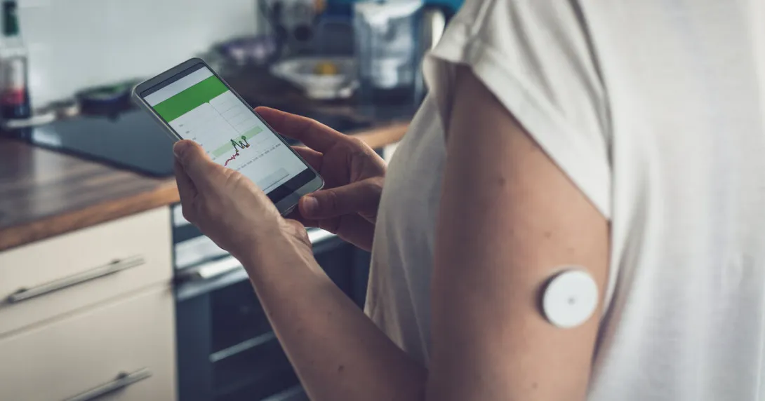A person wearing a CGM patch is checking their blood glucose level on a mobile app A person wearing a CGM patch is checking their blood glucose level on a mobile app