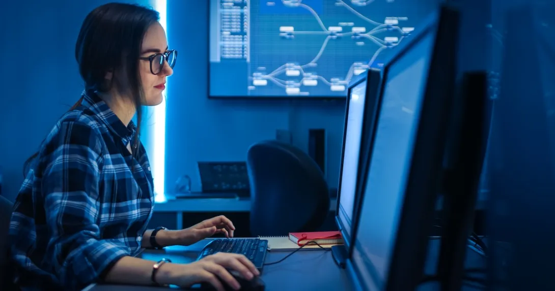 Person sitting at a computer while in a dark room Person sitting at a computer while in a dark room