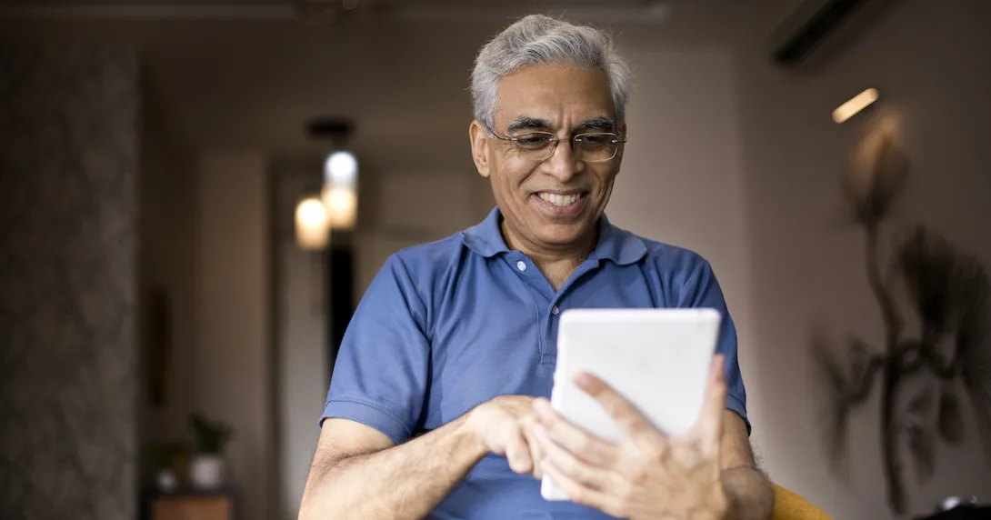 Person at home smiling and looking at a tablet