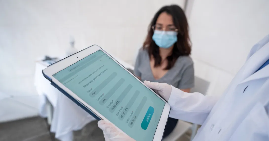 Healthcare provider on a tablet with a patient sitting in a room Healthcare provider on a tablet with a patient sitting in a room