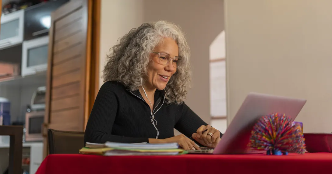Person sitting at a table with a red table cloth on it while in a home looking at a computer Person sitting at a table with a red table cloth on it while in a home looking at a computer