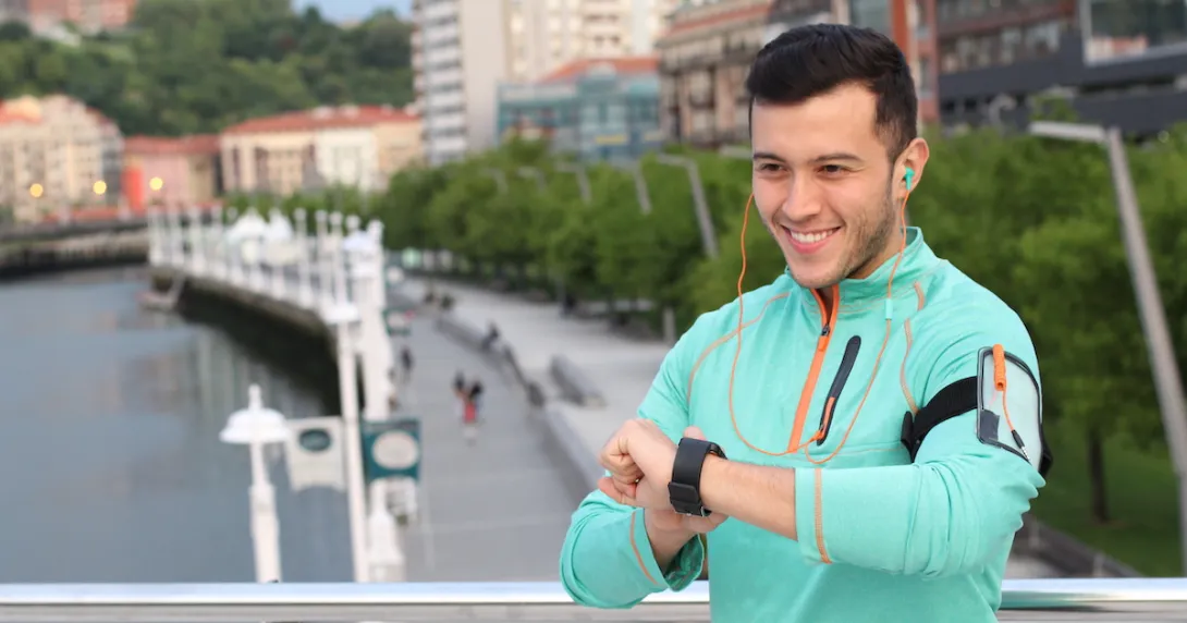 Person wearing a green sweater standing outside looking at a watch Person wearing a green sweater standing outside looking at a watch