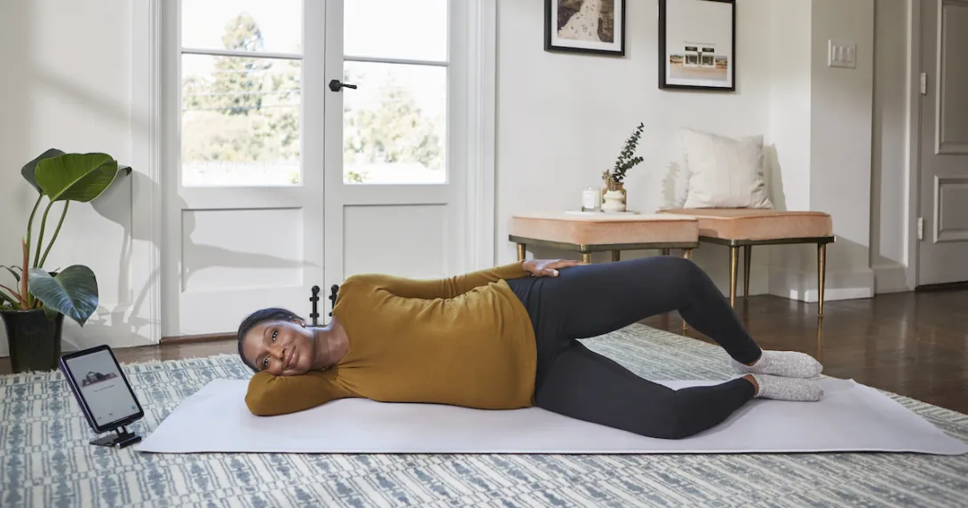 A woman doing a pelvic floor exercise while using Hinge's app on a tablet A woman doing a pelvic floor exercise while using Hinge's app on a tablet