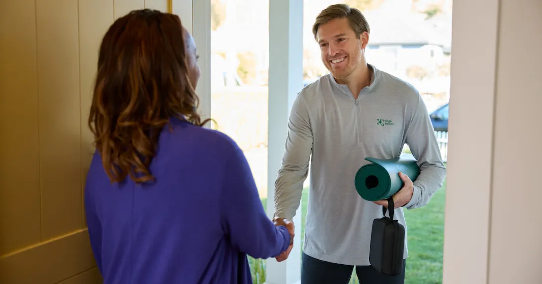A physical therapist greeting a patient at the door with a yoga mat A physical therapist greeting a patient at the door with a yoga mat