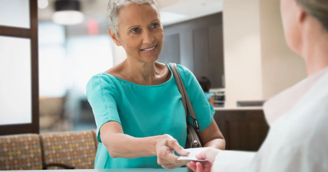 Person handing a piece of paper to a healthcare professional Person handing a piece of paper to a healthcare professional
