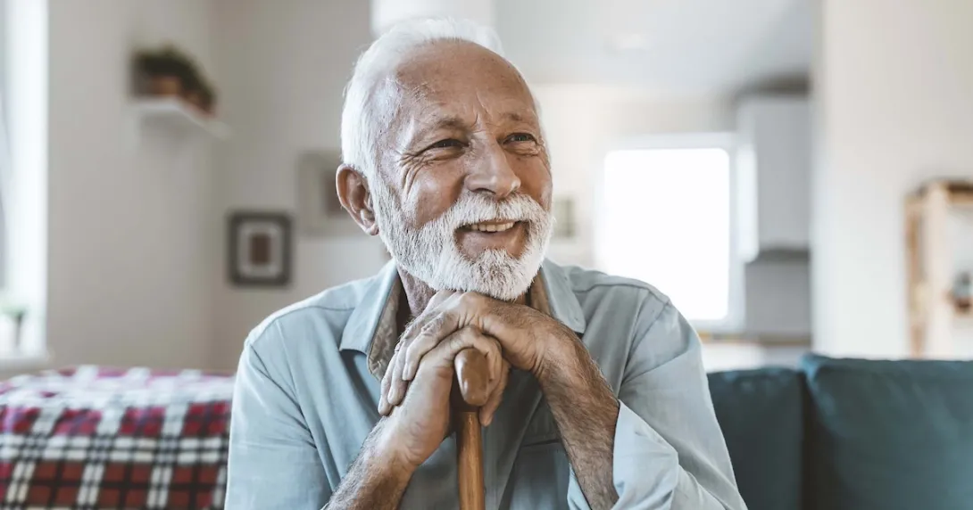 Person sitting on their ouch while holding their cane Person sitting on their ouch while holding their cane