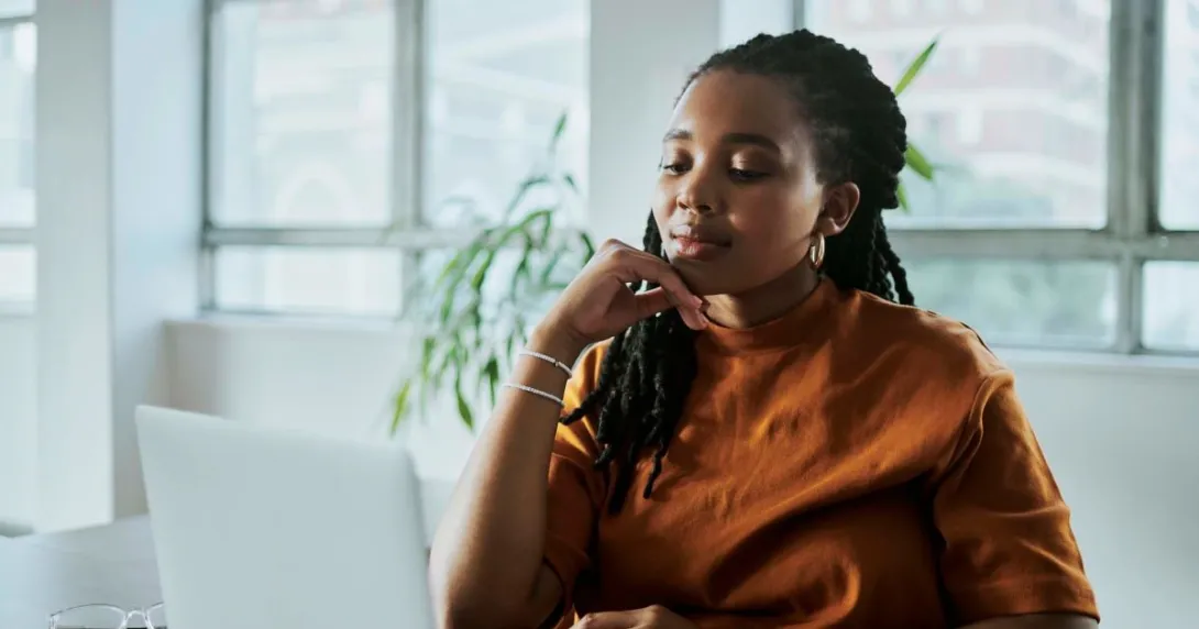 Person in orange shirt looking at computer screen Person in orange shirt looking at computer screen