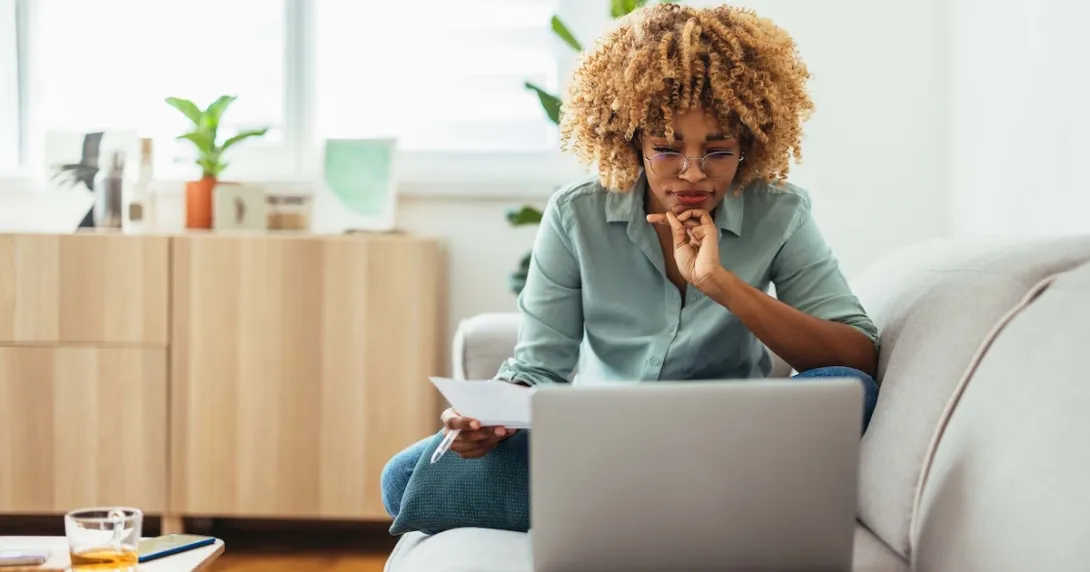 Person sitting on their couch while looking at a computer
