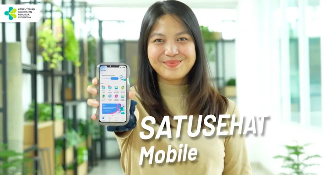 A person holding a mobile phone showing the Satusehat app A person holding a mobile phone showing the Satusehat app