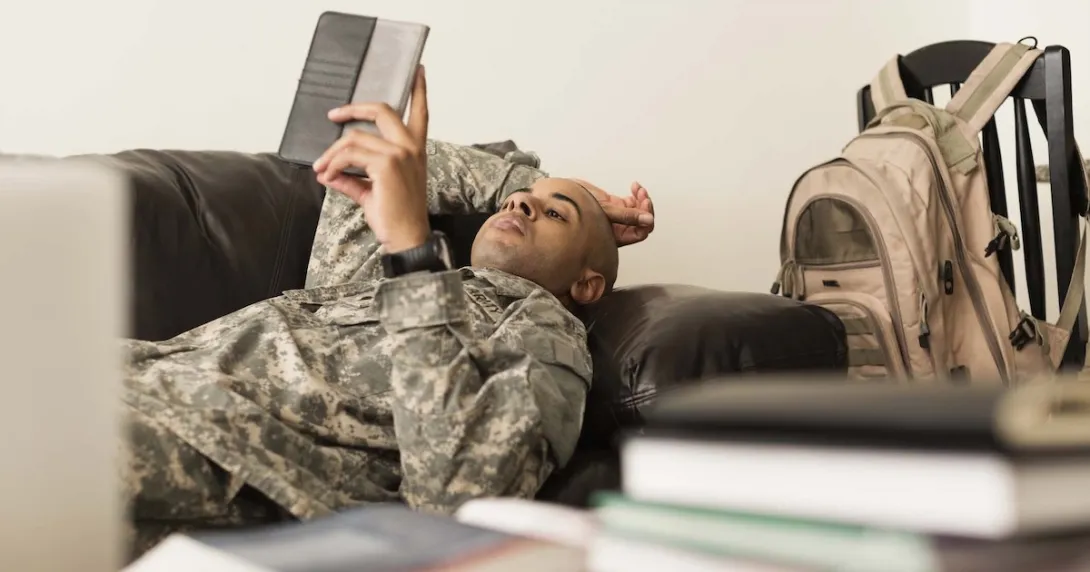 A soldier using a tablet while lying on a sofa. A soldier using a tablet while lying on a sofa.