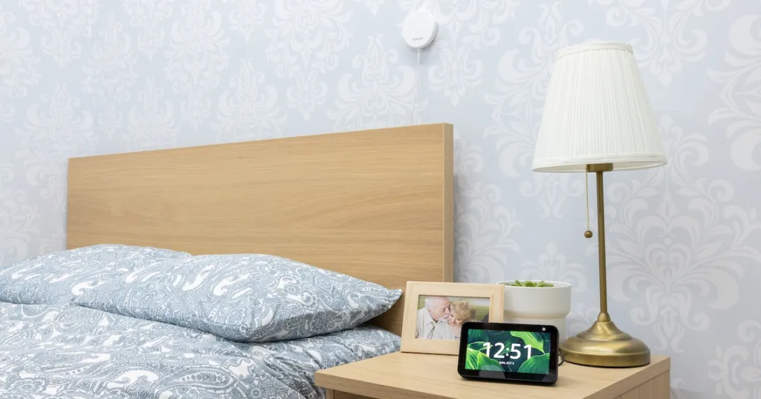 An Alexa device on a bedside table with a Vayyar sensor above the bed. An Alexa device on a bedside table with a Vayyar sensor above the bed.