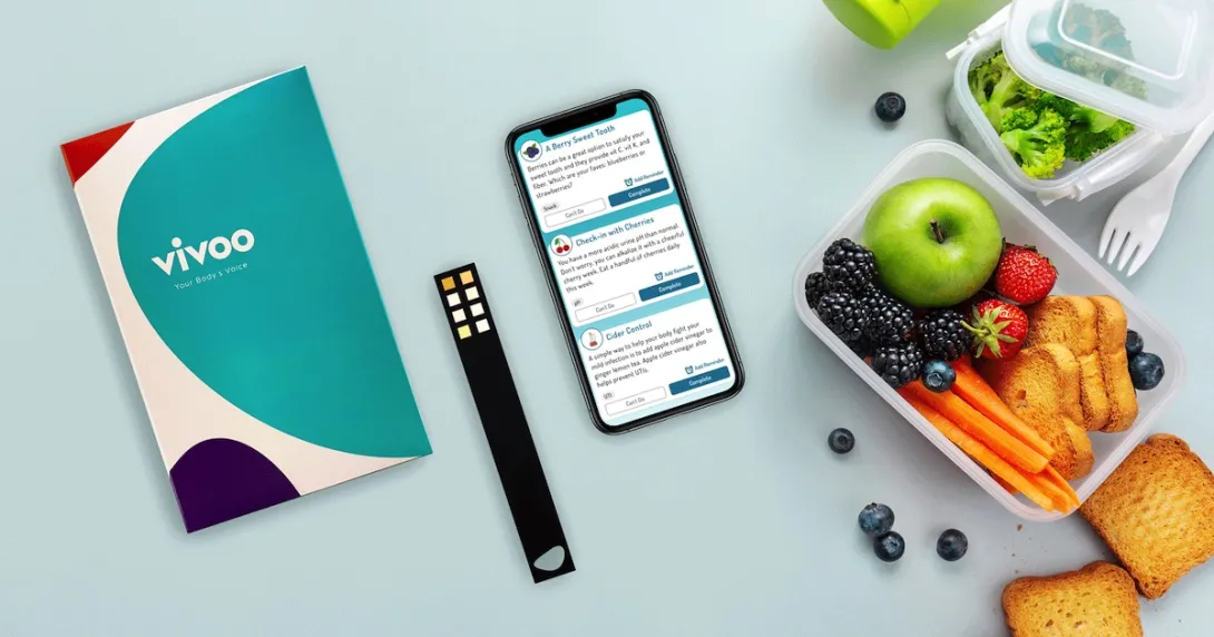 A photo of the Vivoo test kit next to a smartphone and a lunchbox. A photo of the Vivoo test kit next to a smartphone and a lunchbox.