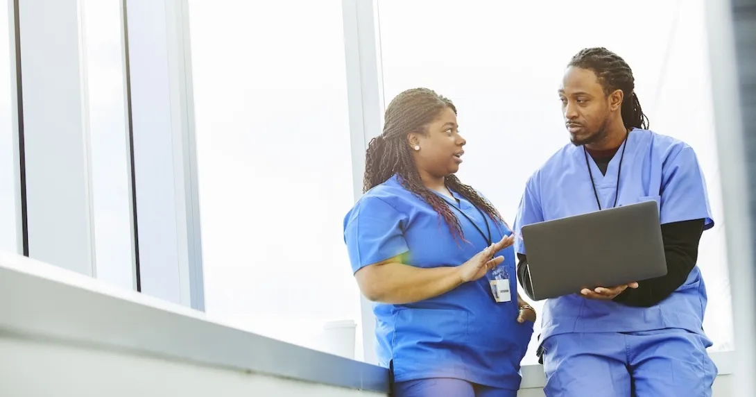 Healthcare professionals conferring while using a laptop computer Healthcare professionals conferring while using a laptop computer
