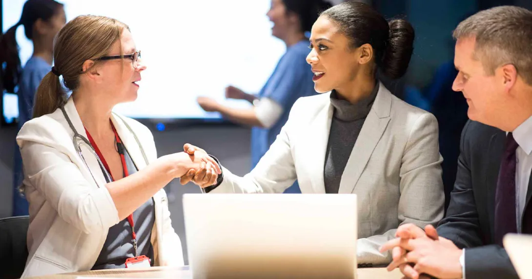 Businesspeople shaking hands in front of a laptop Businesspeople shaking hands in front of a laptop