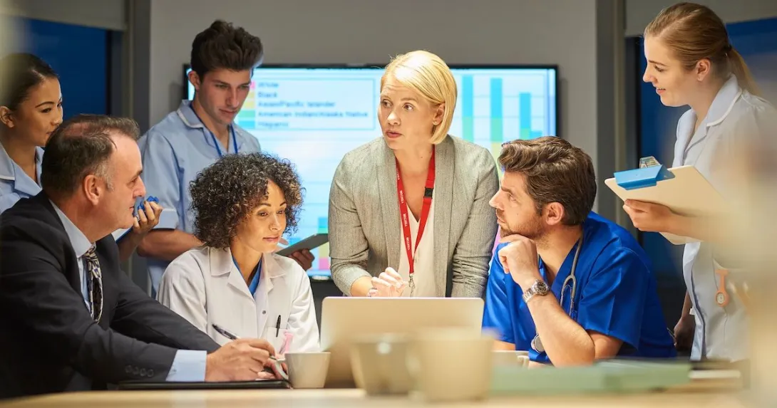 A mixed group of healthcare professionals and business people meet around a conference table. A mixed group of healthcare professionals and business people meet around a conference table.