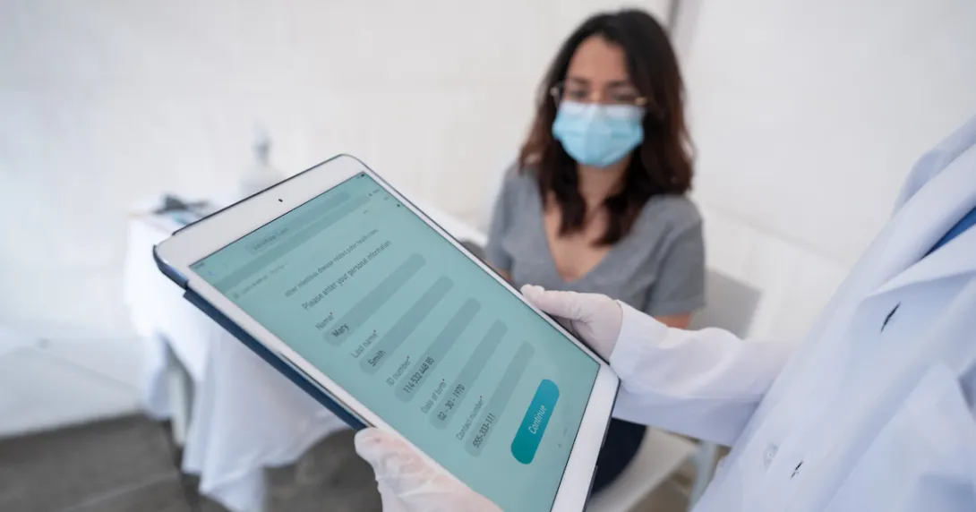 Person being registered for a COVID-19 vaccine at an immunization stand with a tablet computer. Person being registered for a COVID-19 vaccine at an immunization stand with a tablet computer.