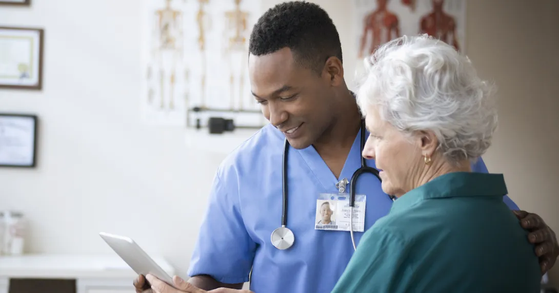 A doctor and a patient look at a tablet in his office. A doctor and a patient look at a tablet in his office.