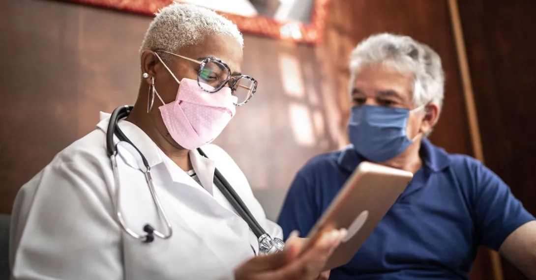 A doctor talking to a patient while holding a tablet. A doctor talking to a patient while holding a tablet.