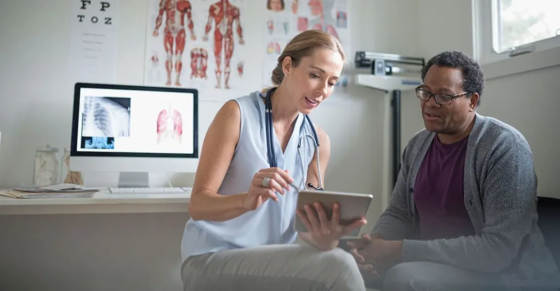 A medical professional looking at a tablet with a patient