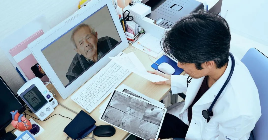 A doctor looking at imaging results while consulting with a patient on his laptop A doctor looking at imaging results while consulting with a patient on his laptop