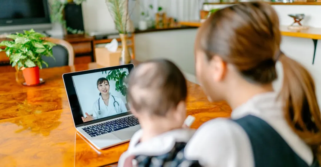 A mother and baby on a video call with a doctor. A mother and baby on a video call with a doctor.