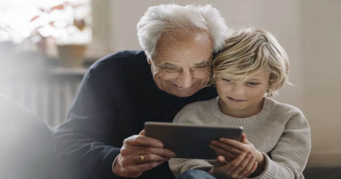 An older man and a child using a tablet An older man and a child using a tablet