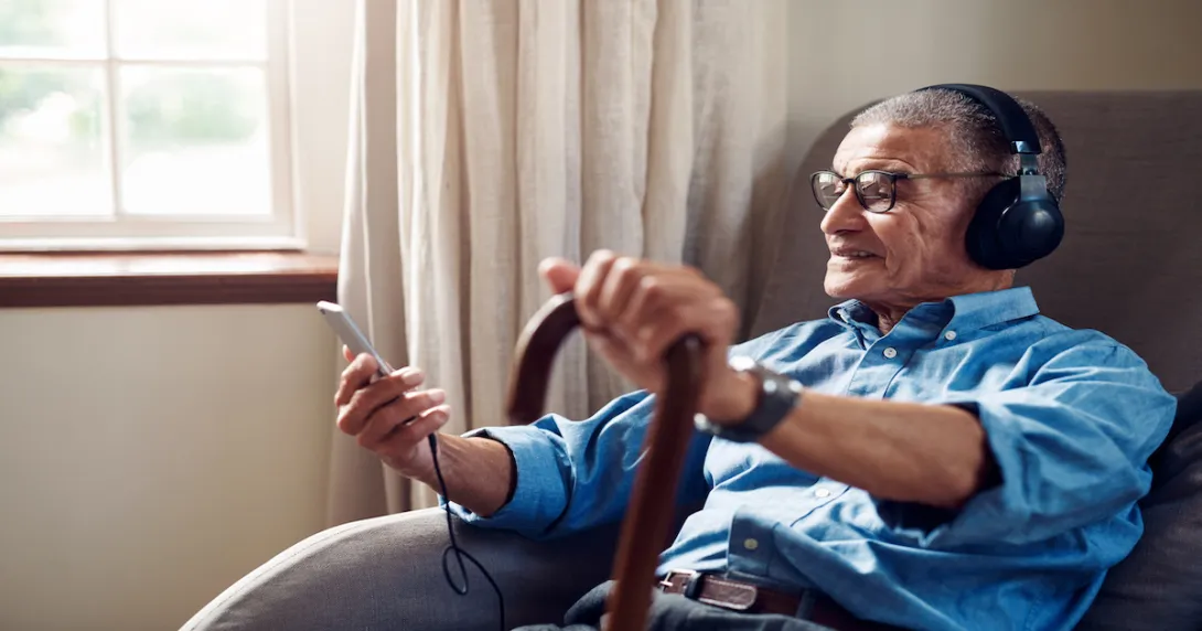 An older man using a smartphone at home.