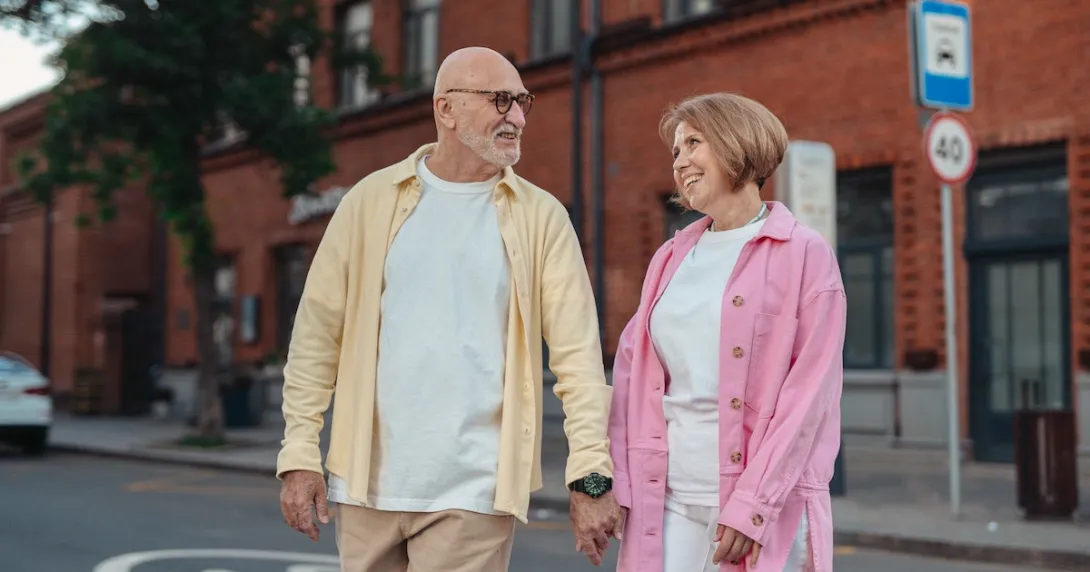 A senior couple holding hands while walking down the street