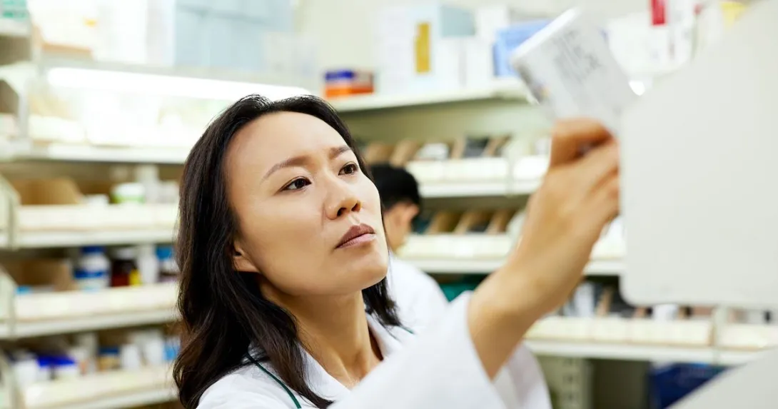 A pharmacist pulling a medication off a shelf. A pharmacist pulling a medication off a shelf.