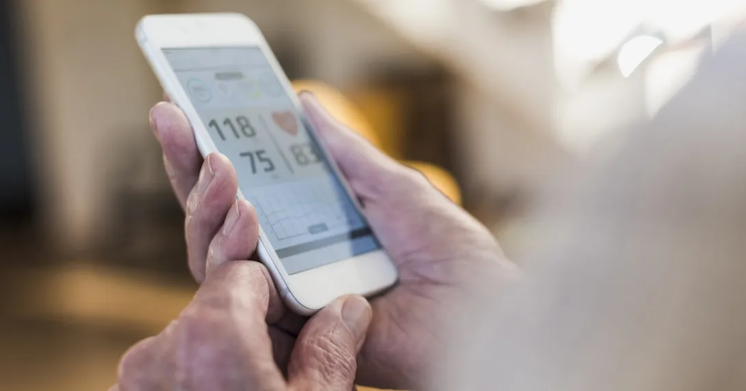 A close-up of a person holding a smartphone displaying heart rate and blood pressure data A close-up of a person holding a smartphone displaying heart rate and blood pressure data