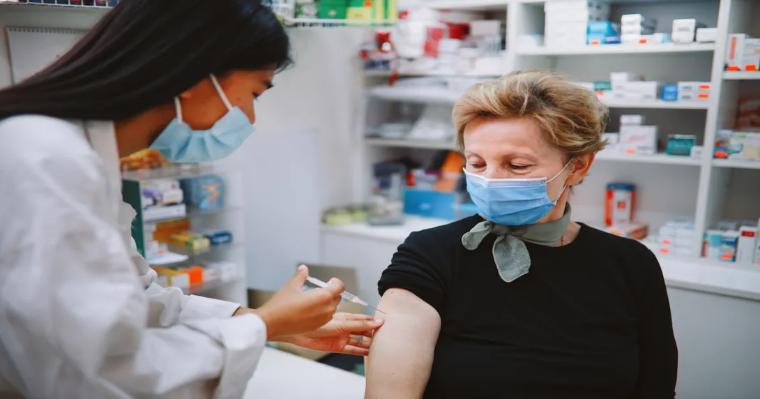 A healthcare provider giving an older woman a vaccine.
