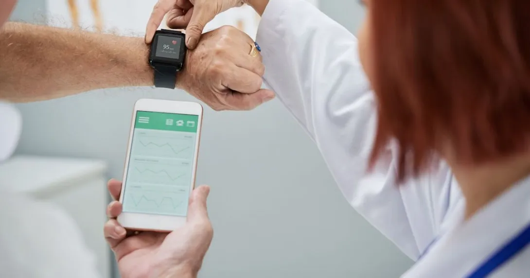A doctor showing a senior patient how to synchronize their health app in a smartphone and a smartwatch A doctor showing a senior patient how to synchronize their health app in a smartphone and a smartwatch