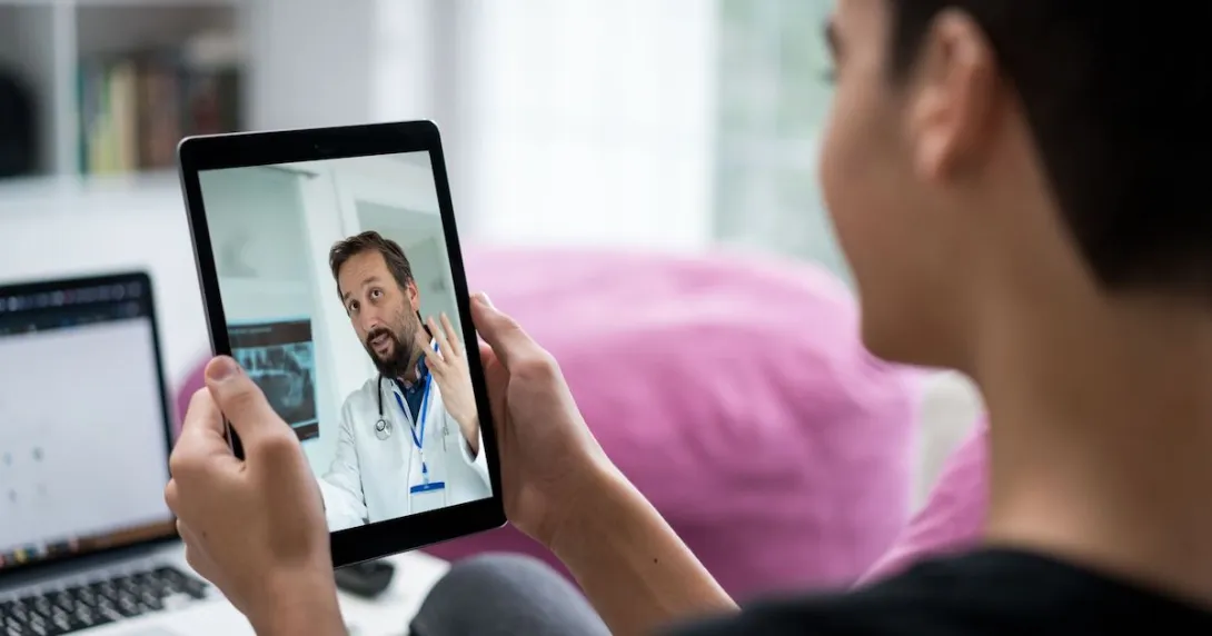 Person holding a tablet while talking to a telehealth provider Person holding a tablet while talking to a telehealth provider
